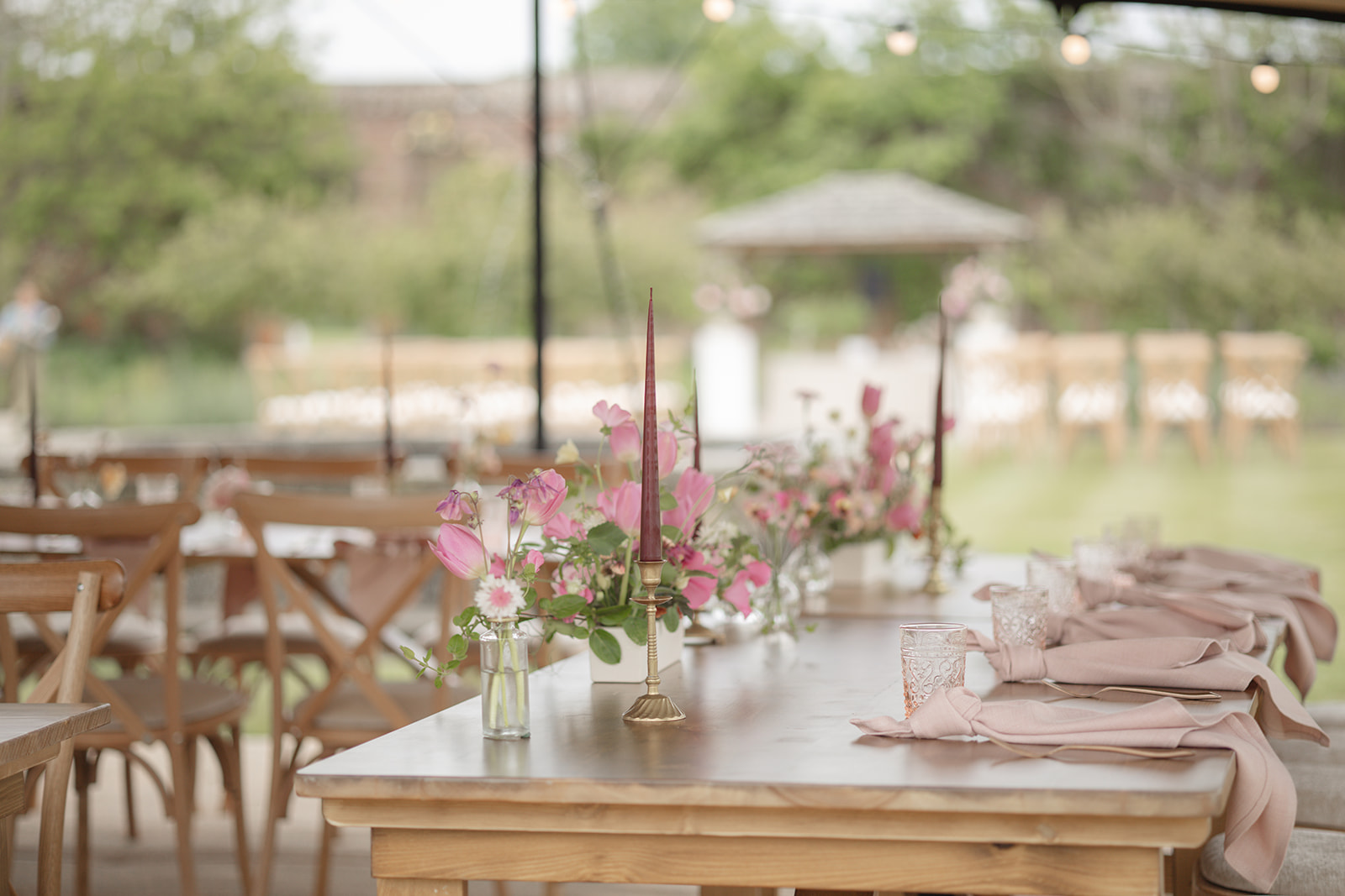 Long rustic wedding tables with pink flowers and cross-back chairs at The Walled Garden, Cowdray