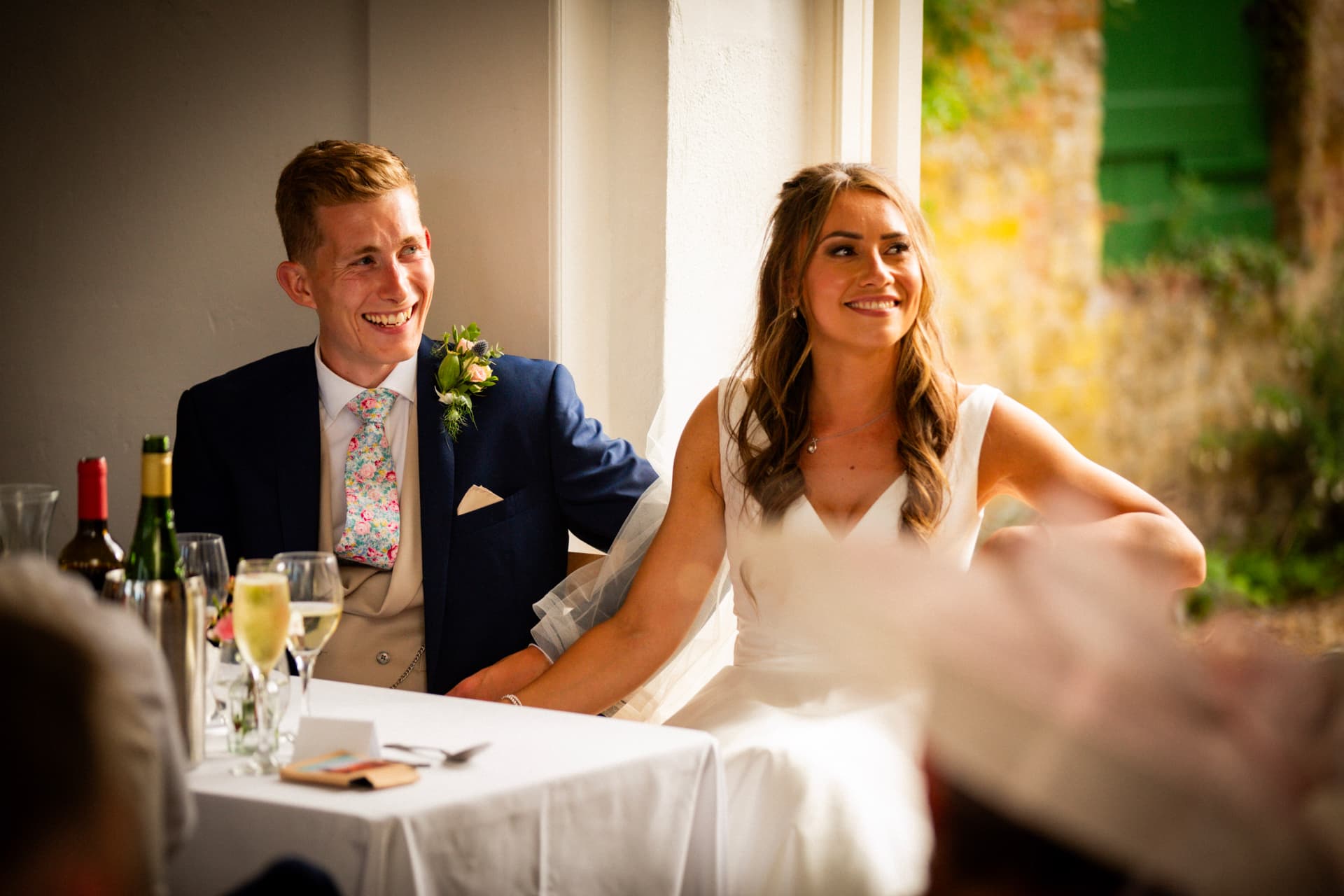 Bride and groom smiling at the top table during speeches at Bignor Park