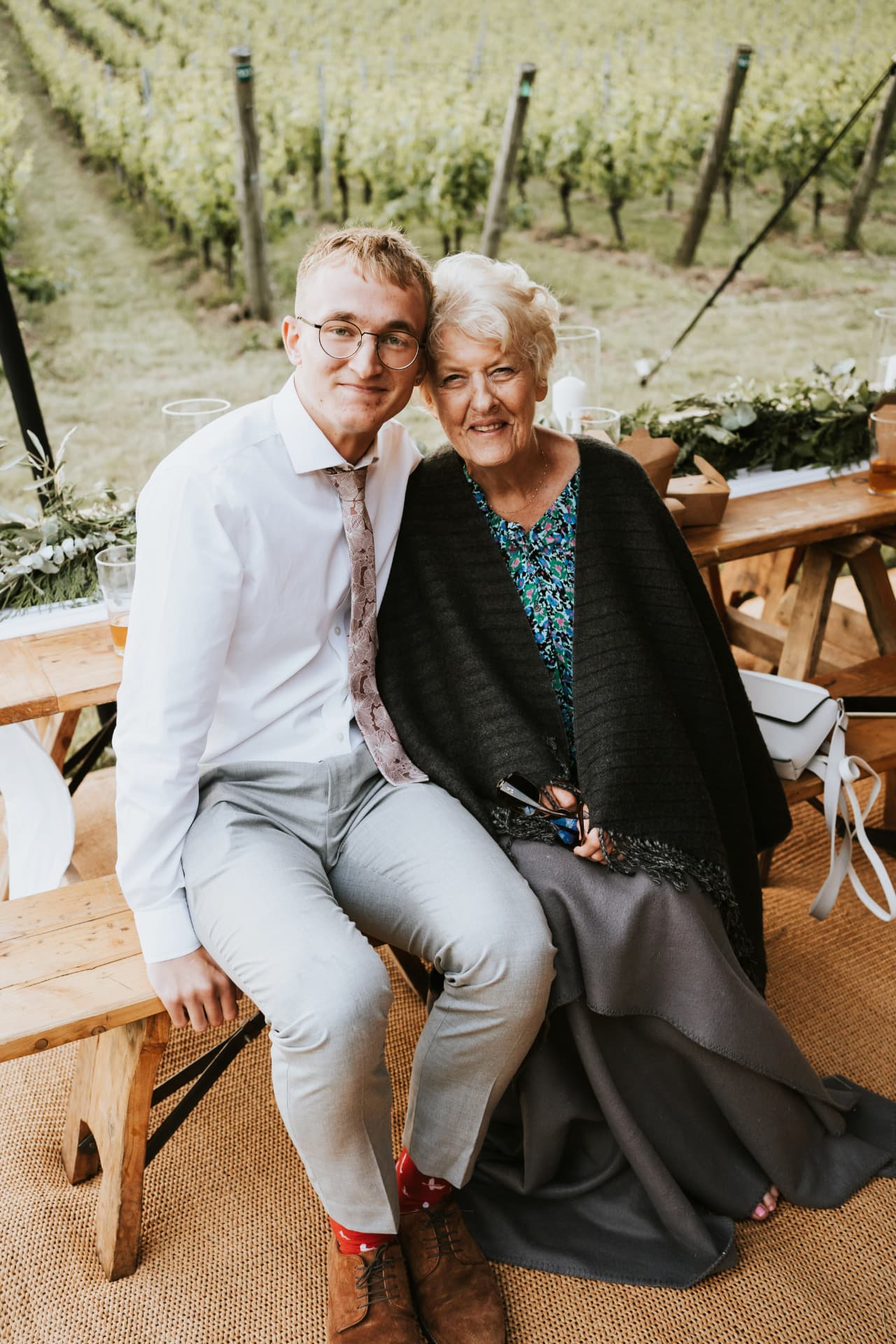 Wedding guests seated on a rustic wooden bench at Wiston Estate
