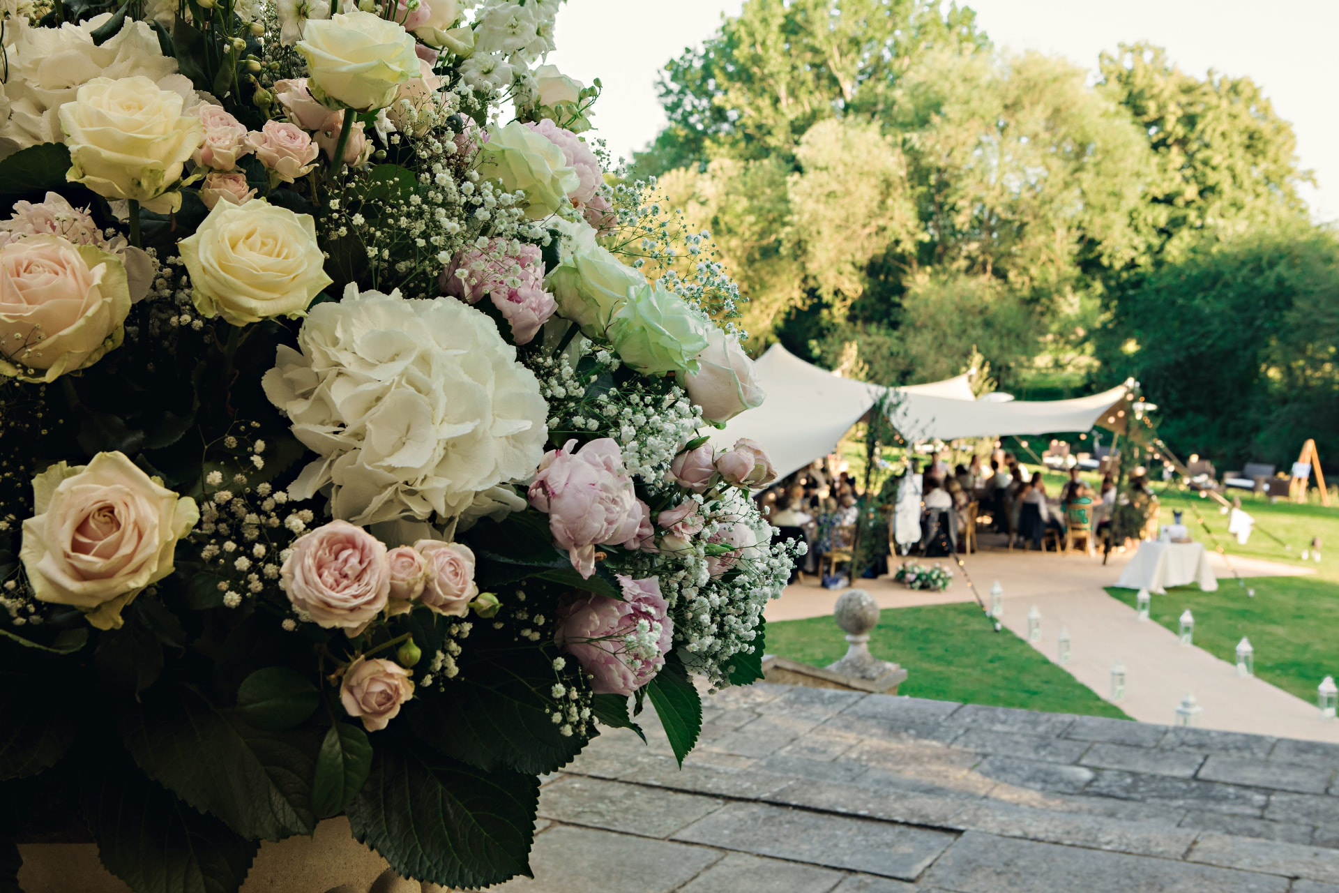Floral arrangement with a stretch tent wedding reception in the background