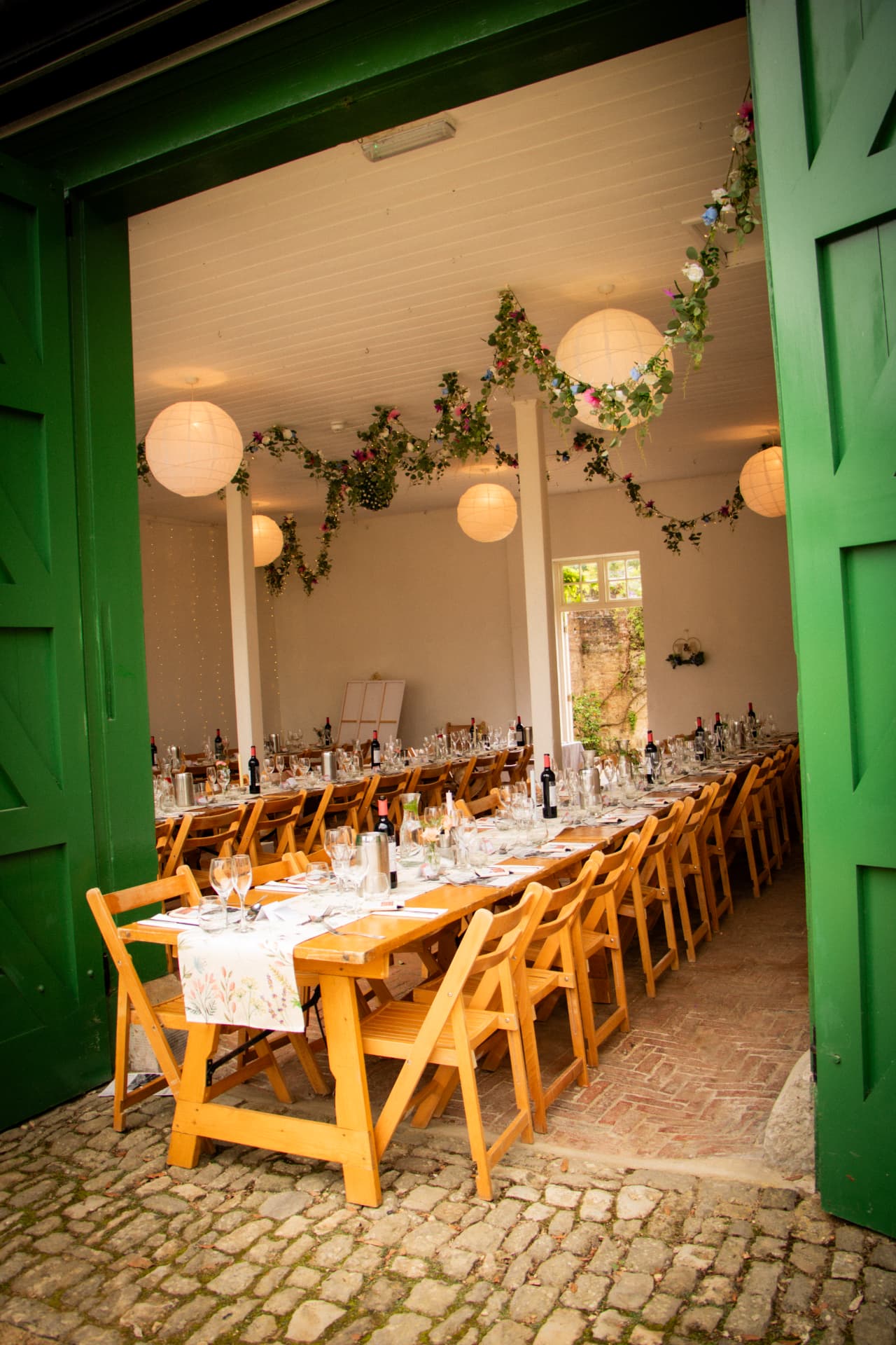 Rustic wedding tables and chairs seen through green barn doors at Bignor Park
