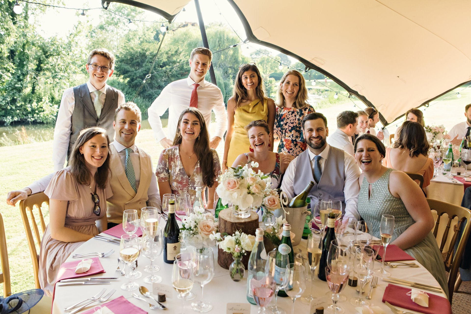 Wedding guests seated around a decorated table under a stretch tent