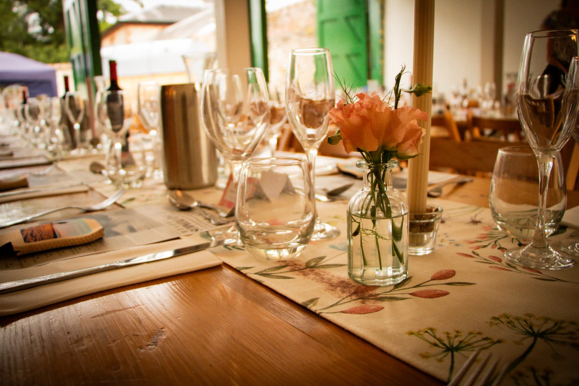 Glassware, candles and flowers laid along a rustic wooden wedding table at Bignor Park