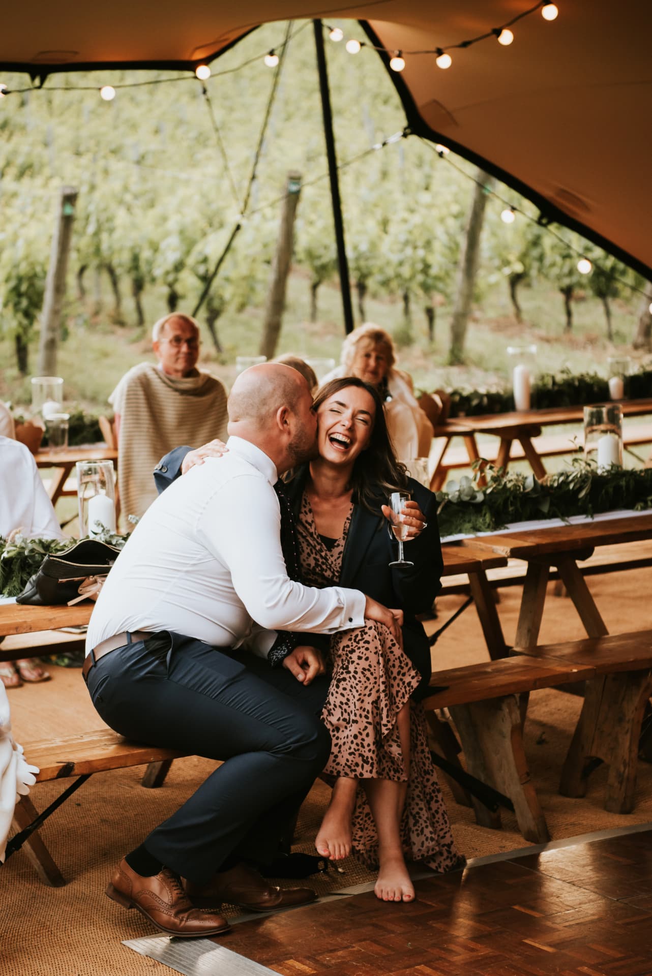Wedding guests laughing together at a rustic table at Wiston Estate