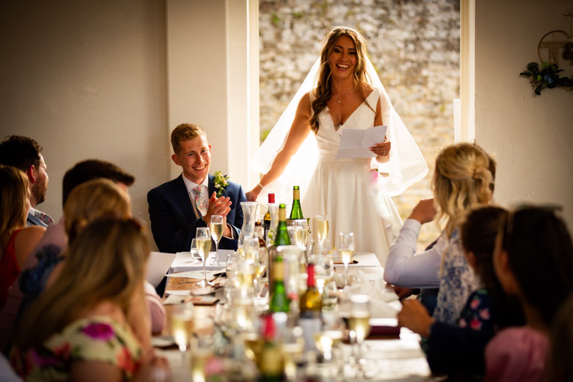 Bride giving her speech to guests seated along a long wedding table at Bignor Park