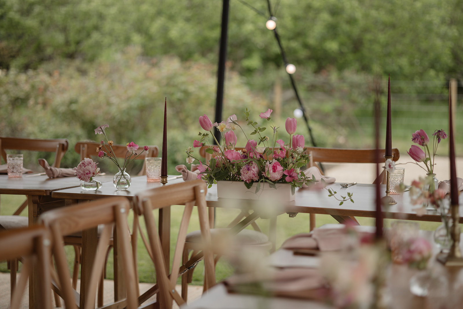 Wedding table styling with pink tulips and candles on rustic tables at The Walled Garden, Cowdray