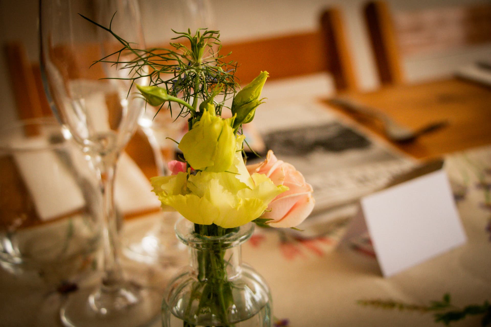 Close-up of flowers in a glass bottle on a rustic wedding table at Bignor Park