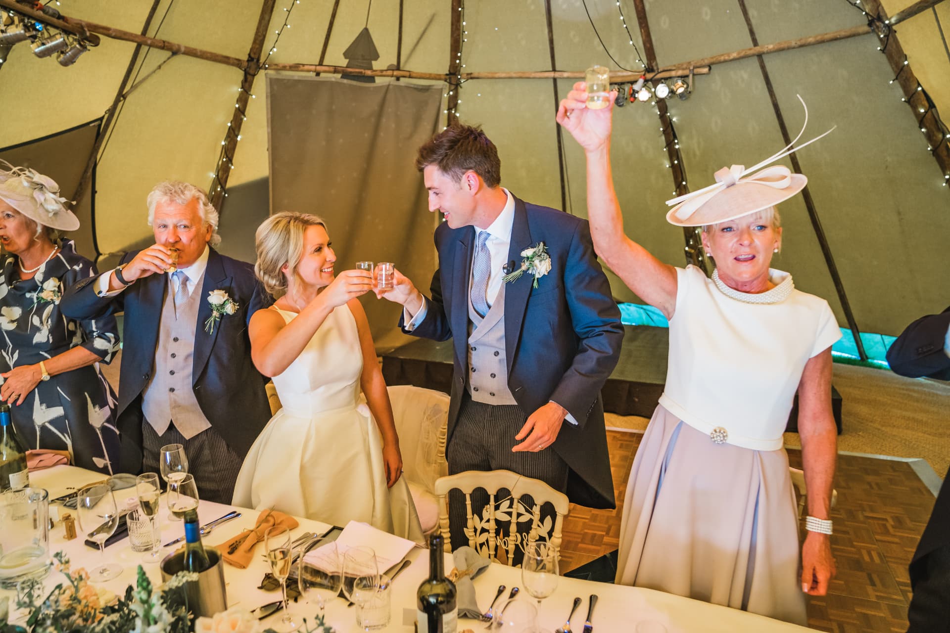 Wedding party raising a toast at a tipi reception at Sumner's Ponds