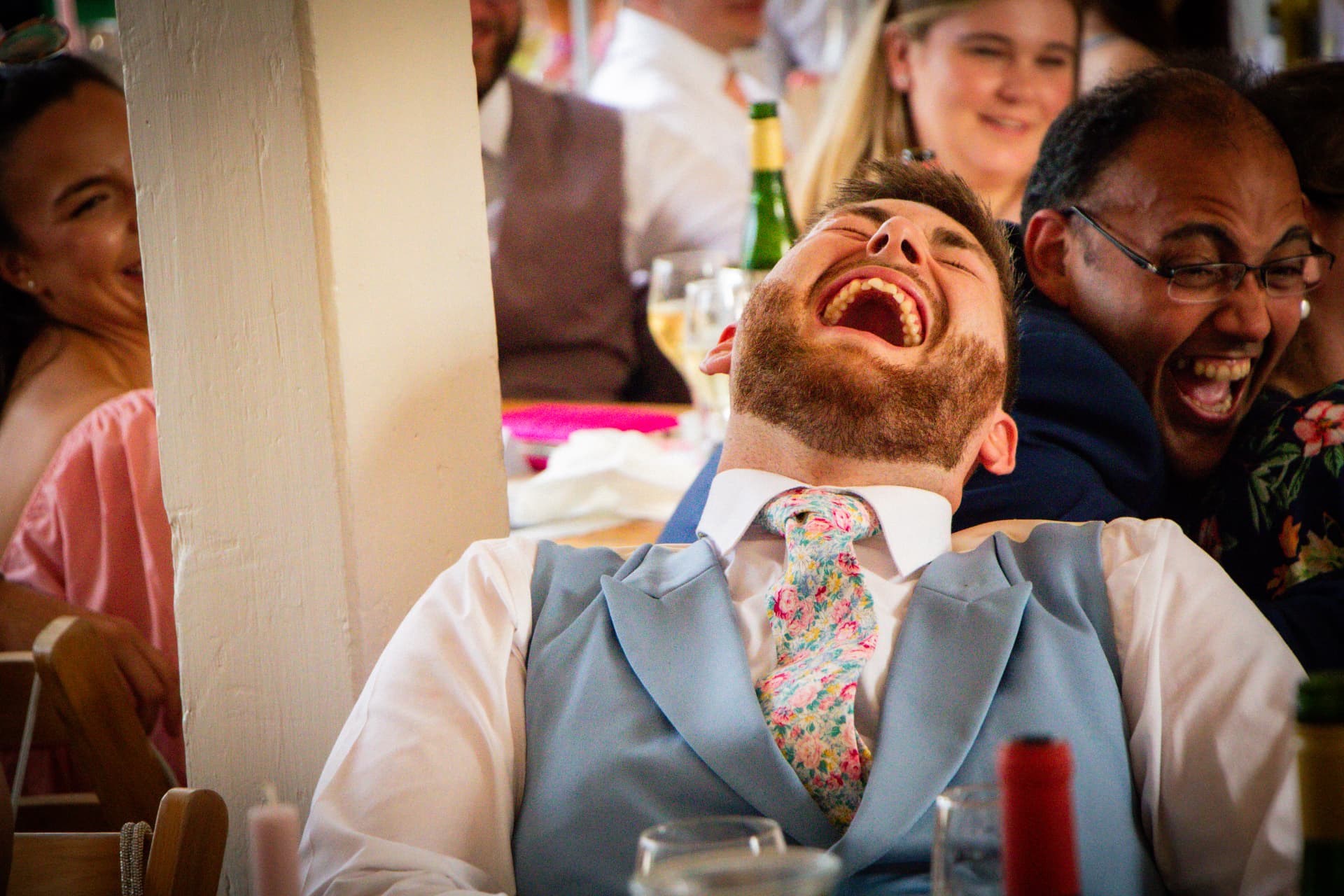 Wedding guests laughing together during the speeches at Bignor Park