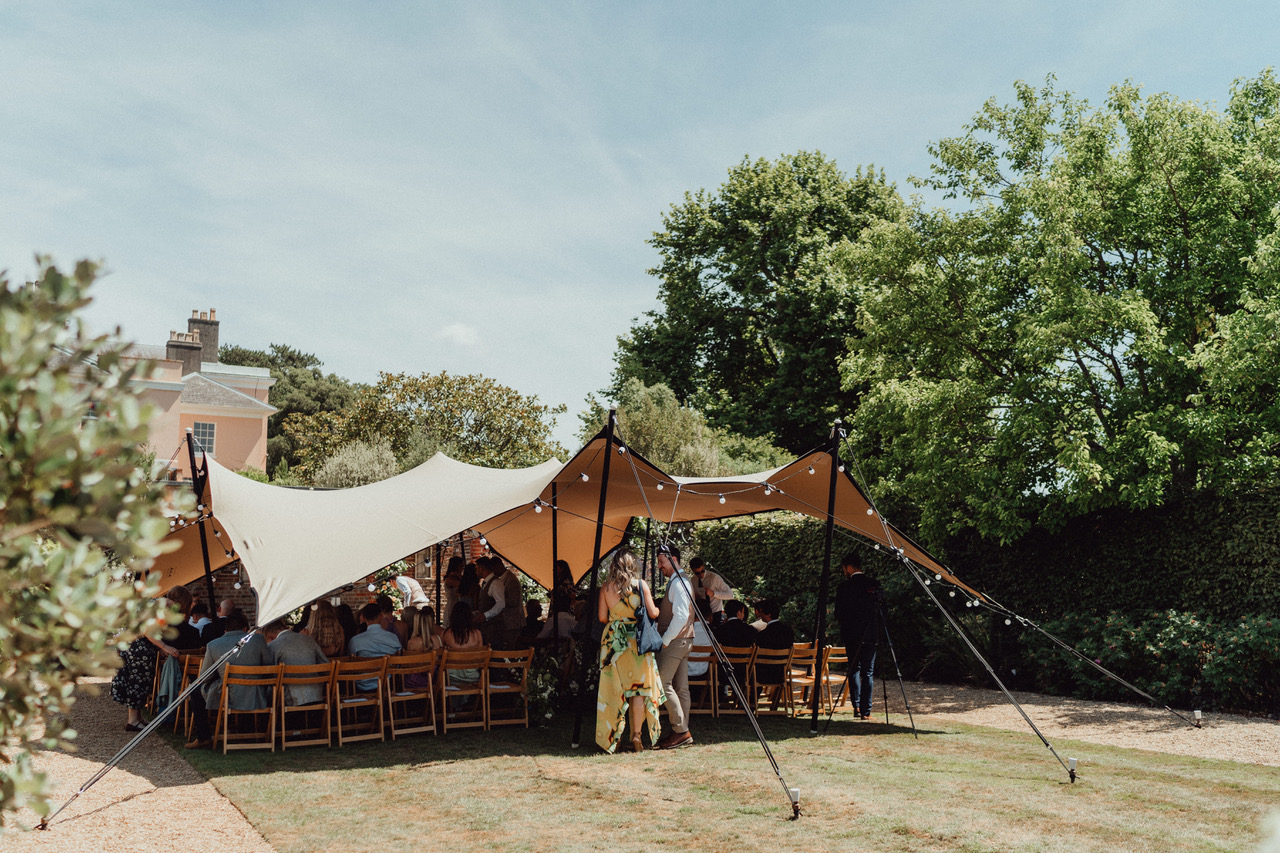 Guests gathered under a stretch tent for an outdoor wedding reception at Bignor Park